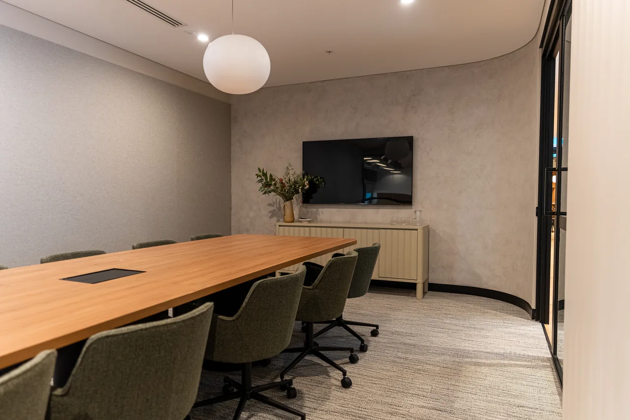 Boardroom with a long timber table, credenza and wall-mounted screen