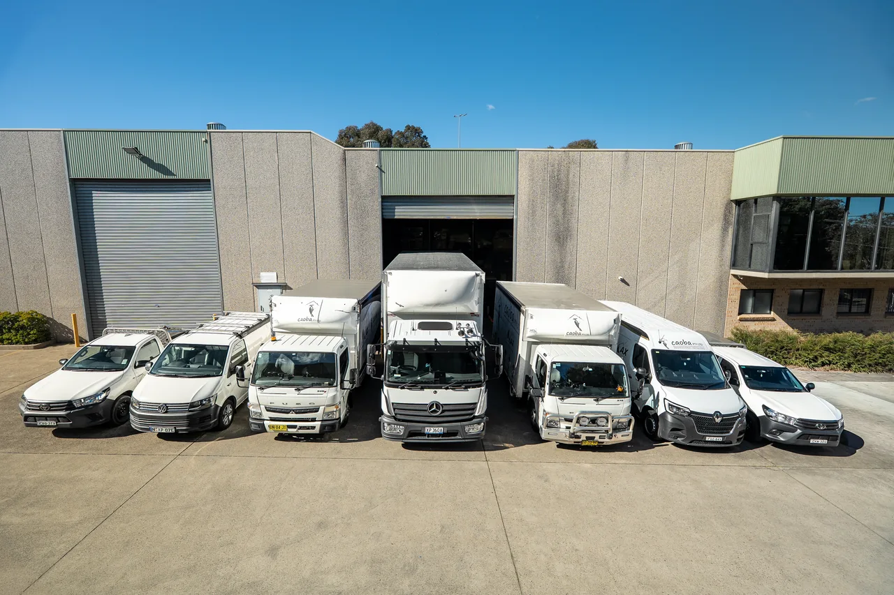 Caoba fleet of utes, vans and trucks lined up outside the warehouse