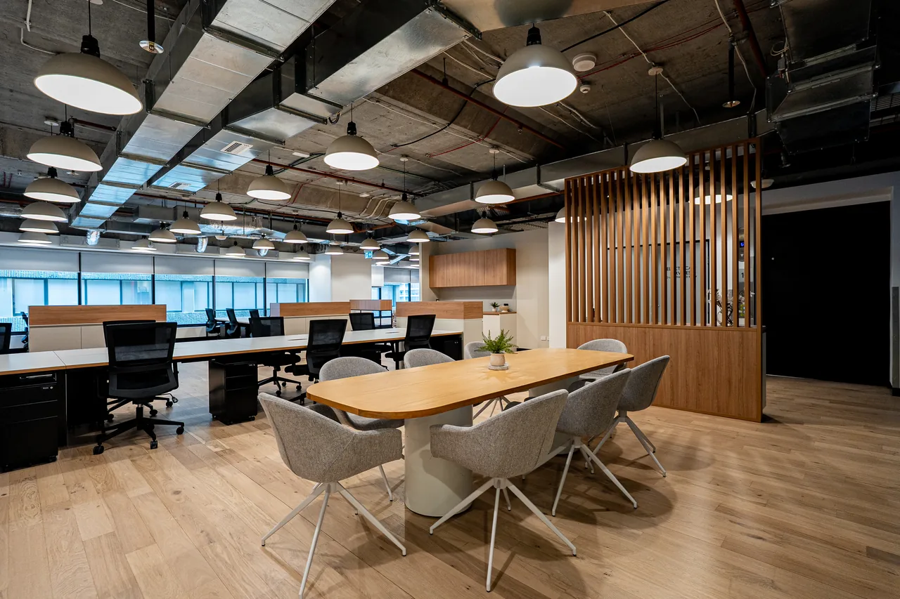 Collaboration table with upholstered chairs beside a timber slat screen