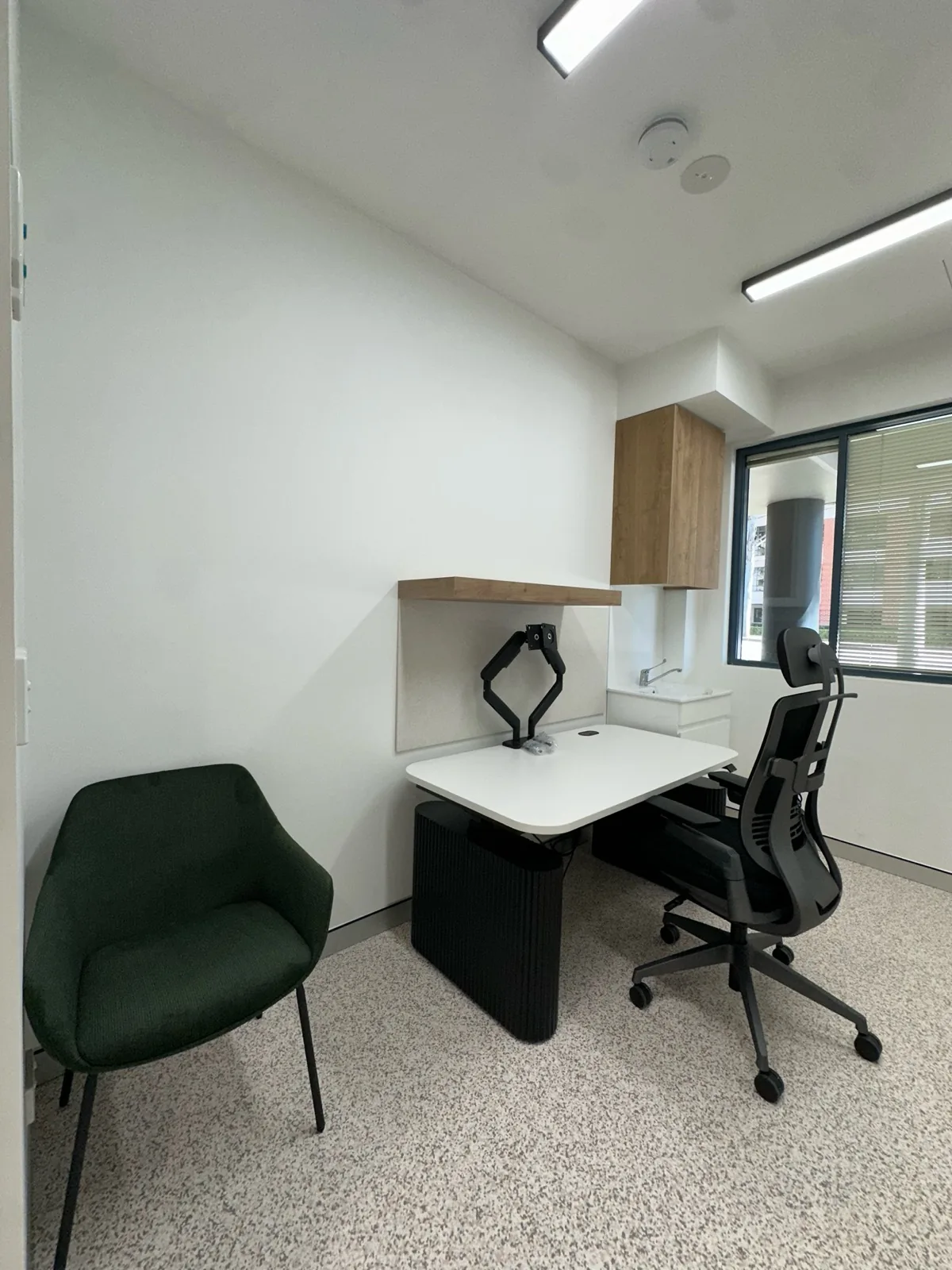 Medical consulting room fitted with desk, chairs and storage