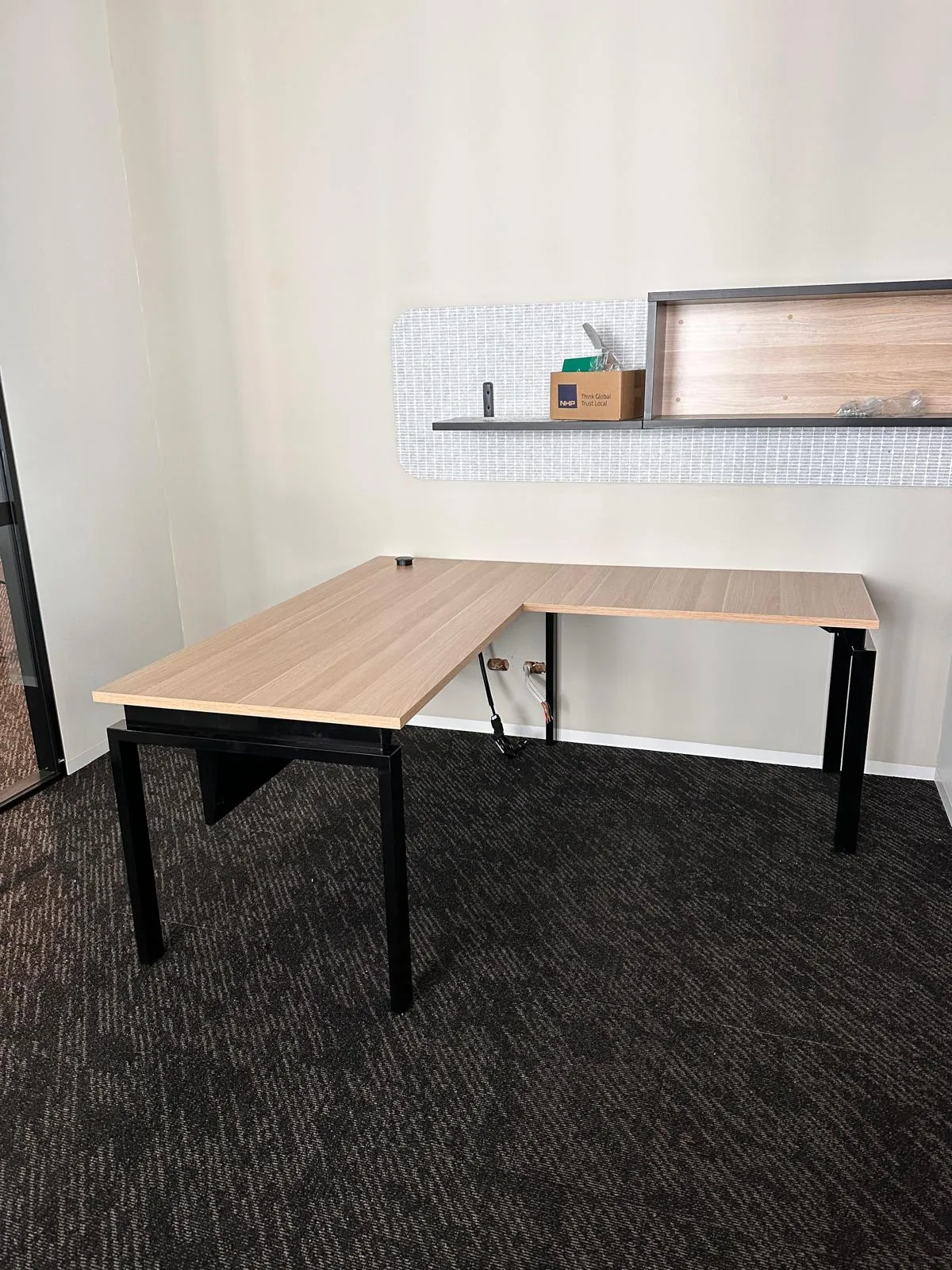 Corner office desk installed with a wall-mounted shelf