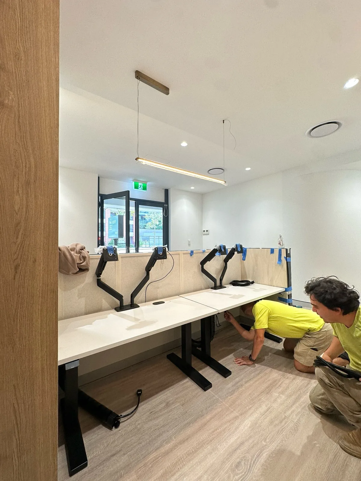 Caoba installer fitting a run of desks with monitor arms