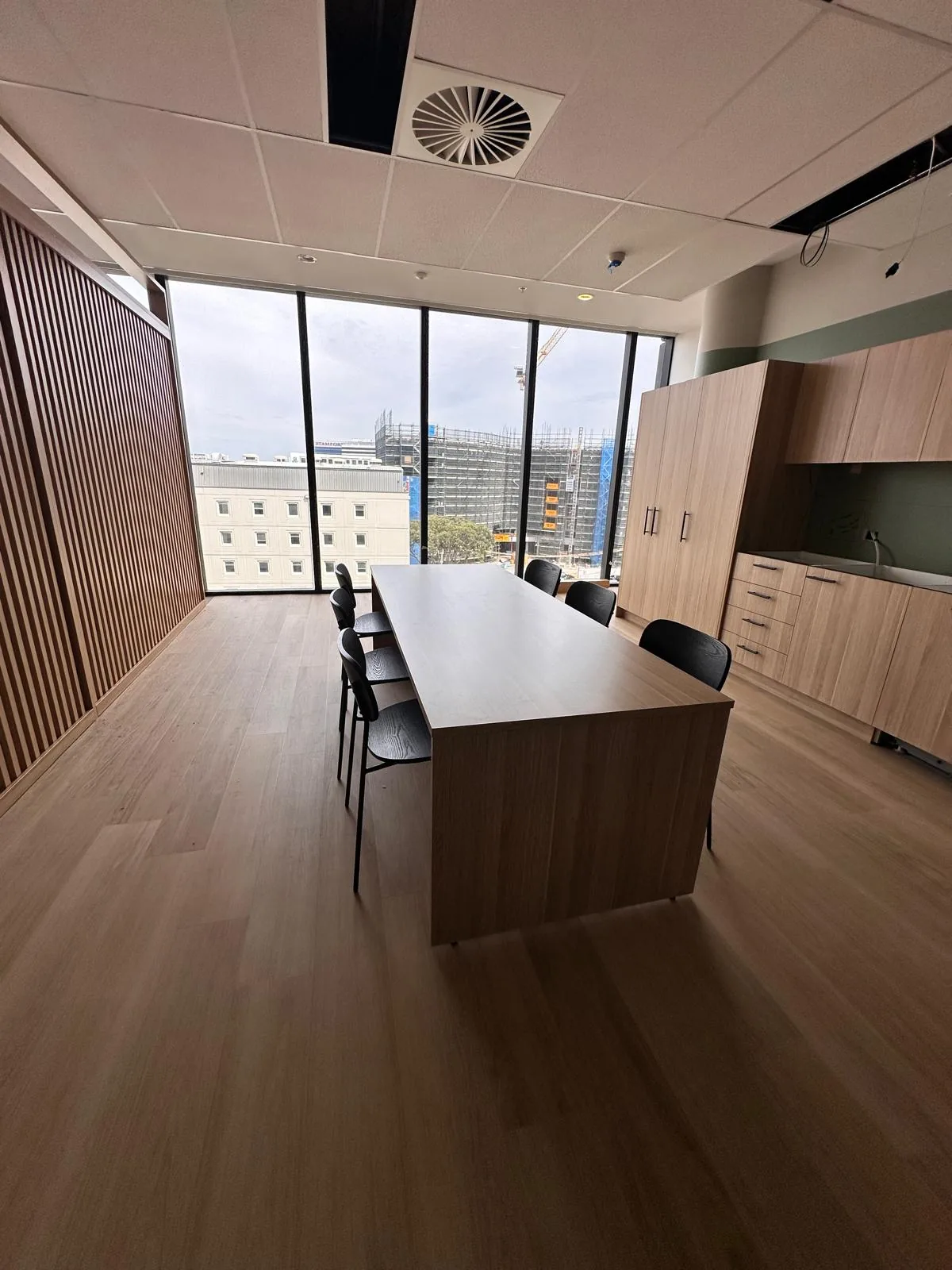 Meeting table and timber joinery beside full-height windows