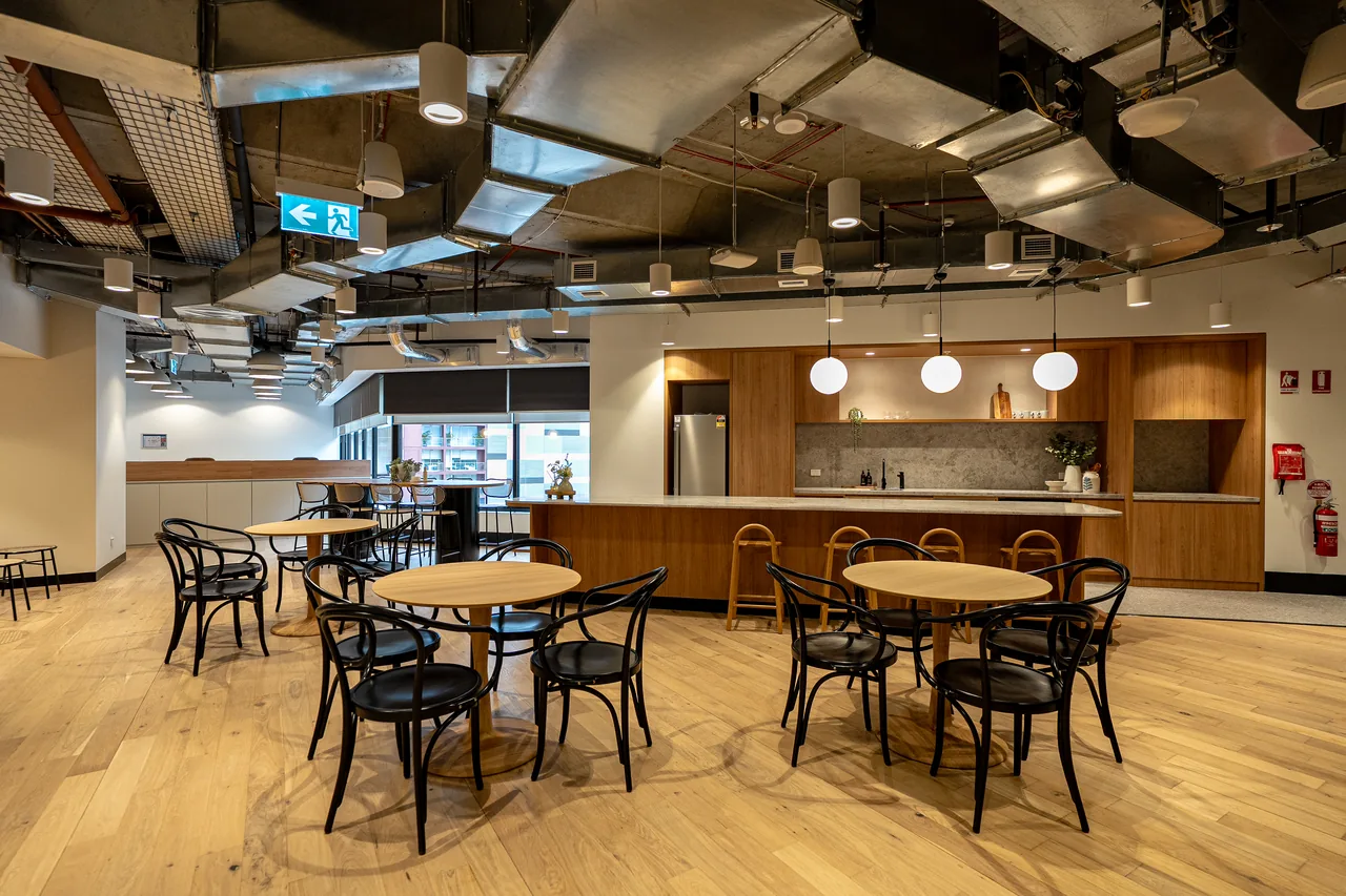 Office breakout kitchen with timber joinery, island bench and café tables
