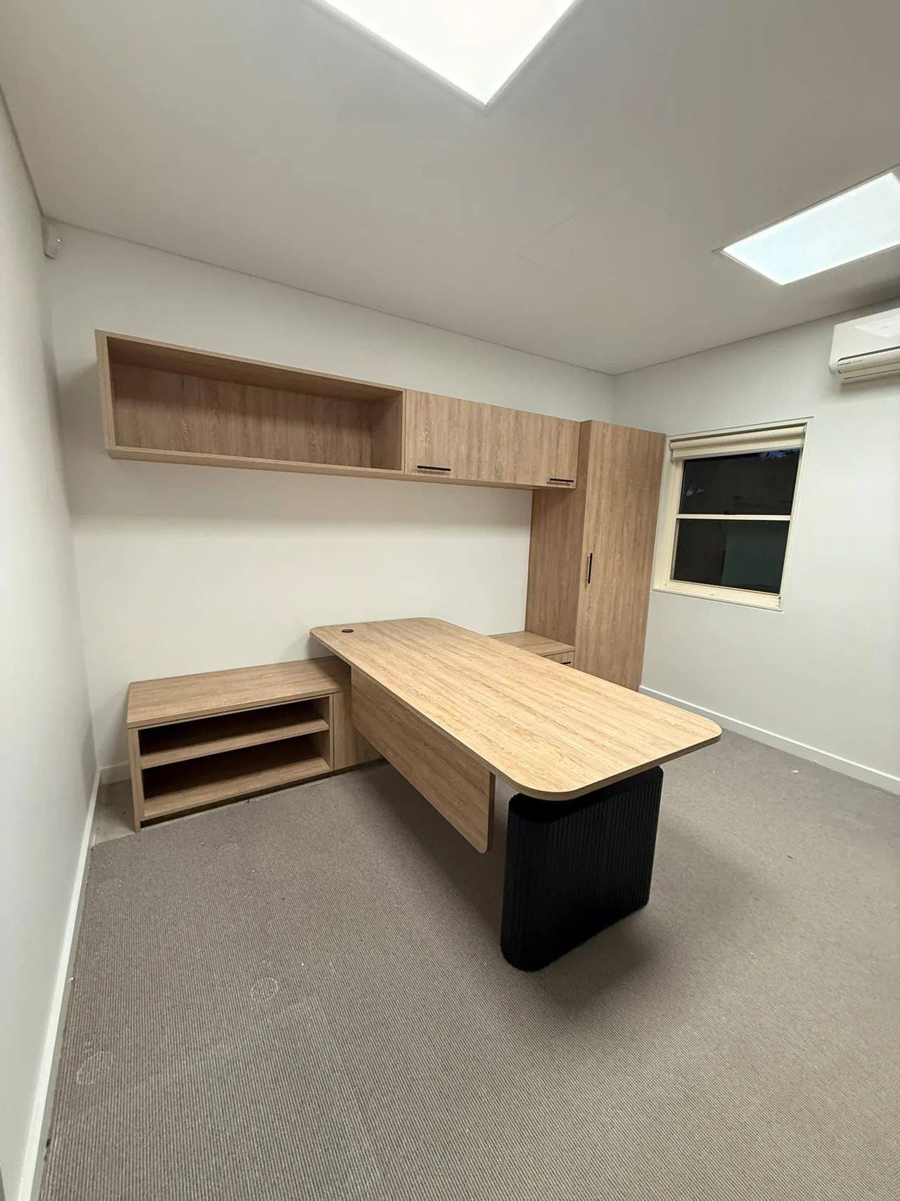 Office desk, low credenza and overhead cabinets fitted in a private office