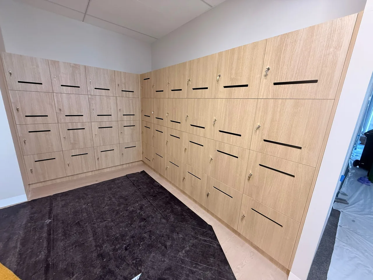 Wall of timber-look keyed lockers installed around the corner of an office