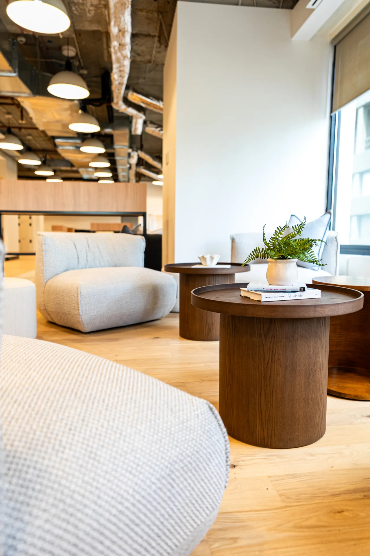 Soft lounge seating and timber side tables in an office breakout zone