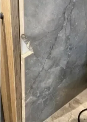 Before: chip through to the substrate on a dark stone panel edge