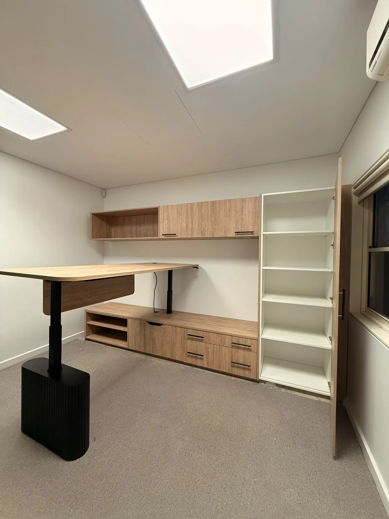 Sit-stand desk with fitted storage joinery and open shelving