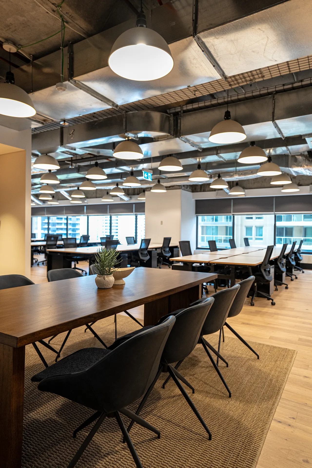 Timber collaboration table with chairs between rows of workstations