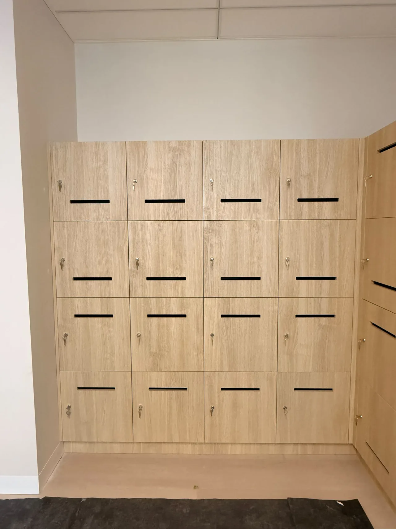 Timber-look office lockers fitted into a wall recess