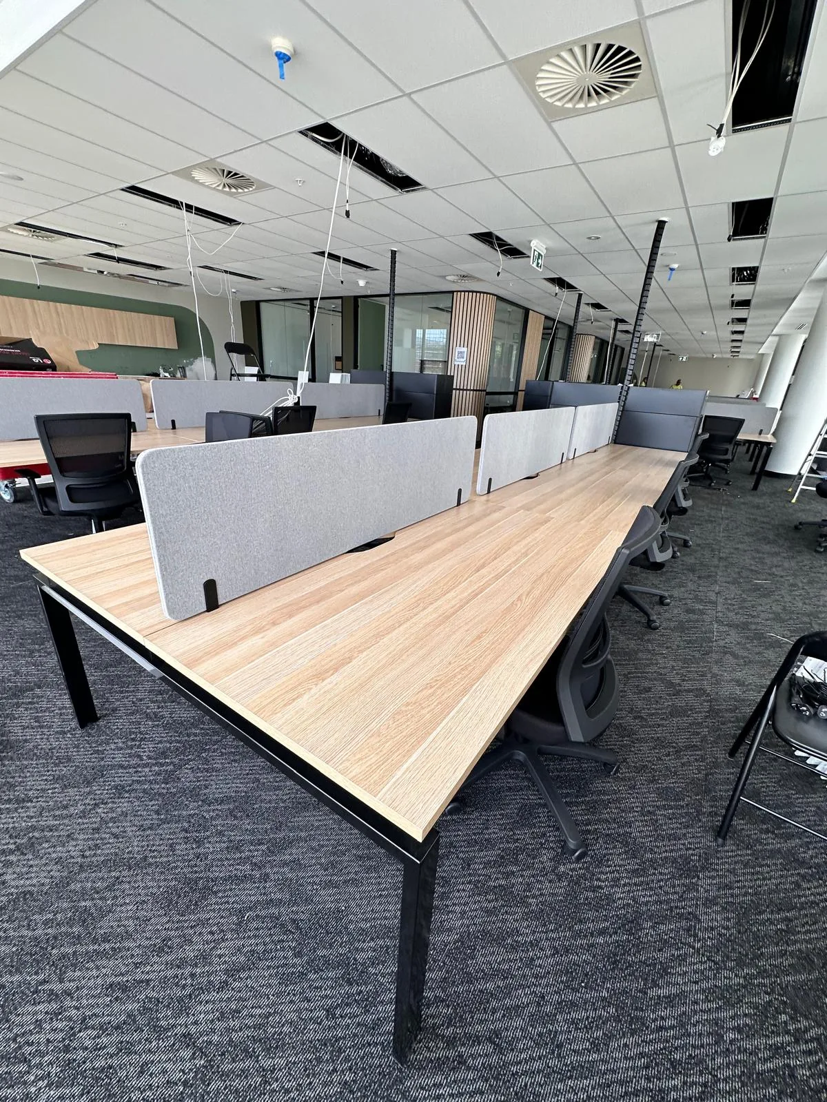Workstation bench with acoustic screens installed along an office floor