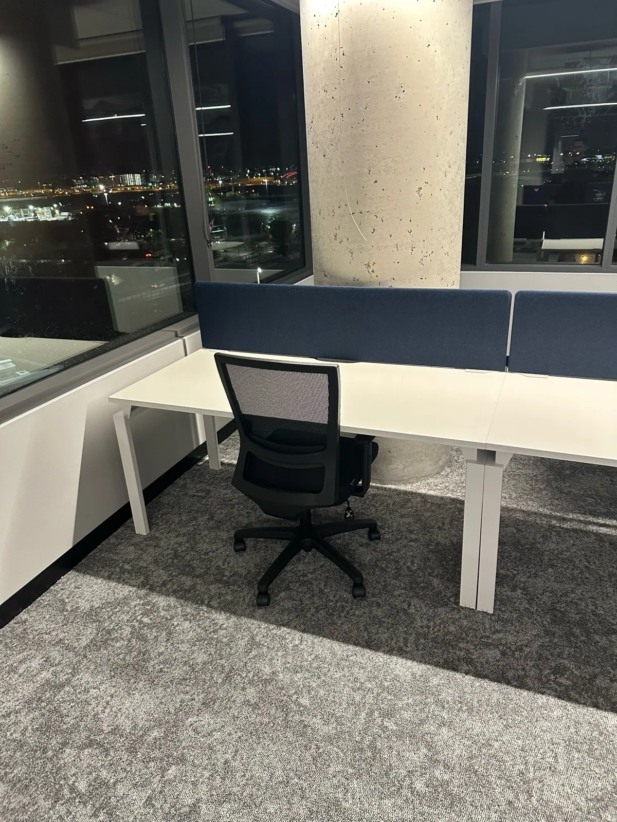 Workstation with desk screen beside a night-time window view
